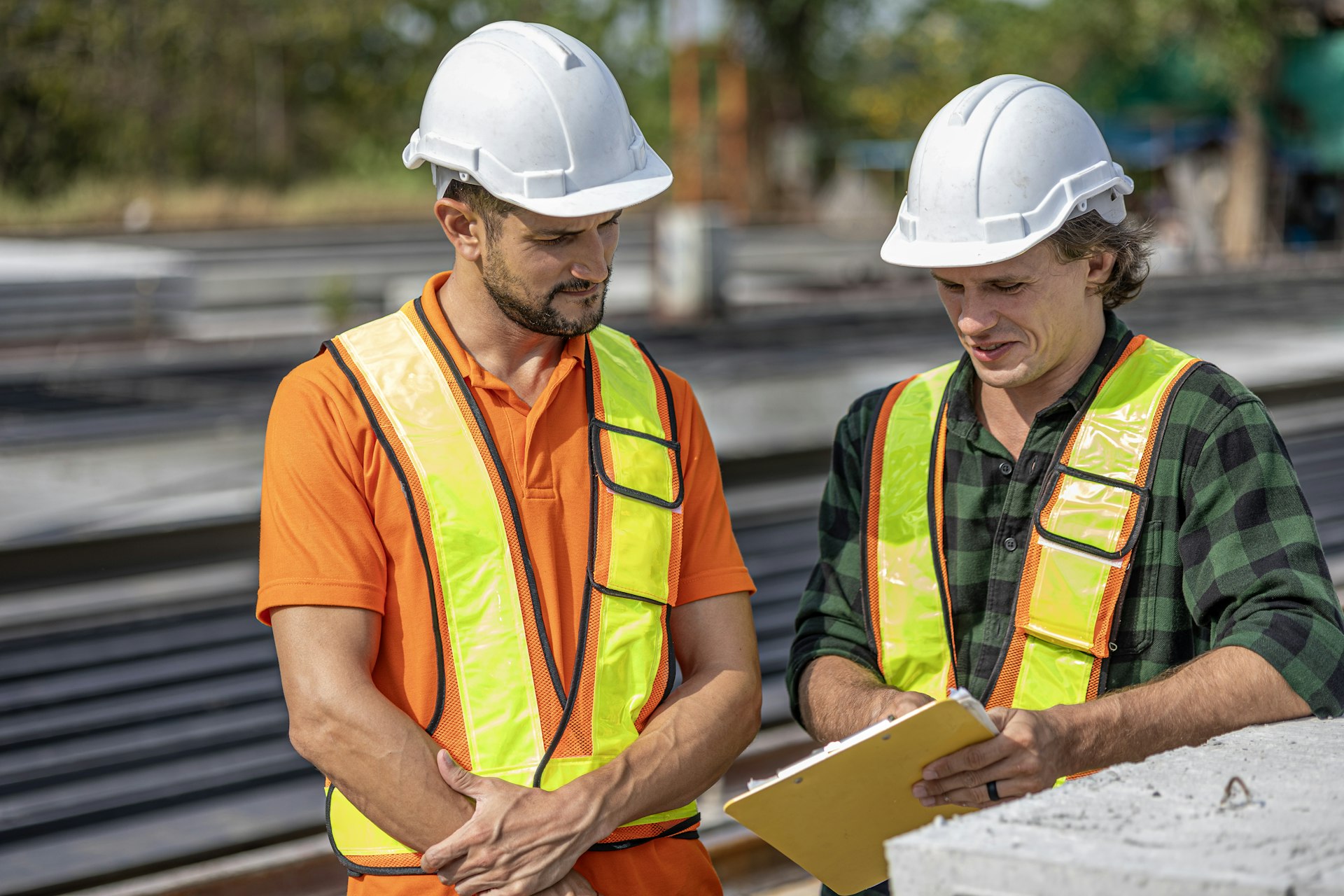 Two engineers in hard hats reviewing plans on a job site